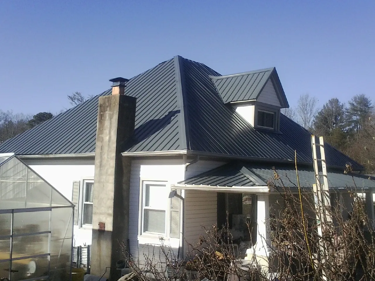 Dark blue standing seam metal roof on a white farmhouse with dormer — Slate & Tile Roof Repair by Roofing Brothers in Grand Blanc