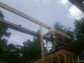 Carpenter setting a ridge beam over a new addition frame — Ice Dam Removal by Roofing Brothers in Grand Blanc