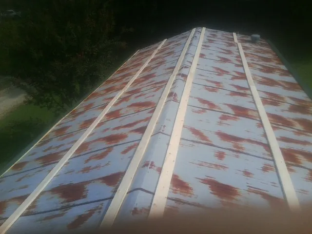 Rusted metal roof panels with new wood purlins before replacement — Storm Damage Roof Repair in Grand Blanc by Roofing Brothers