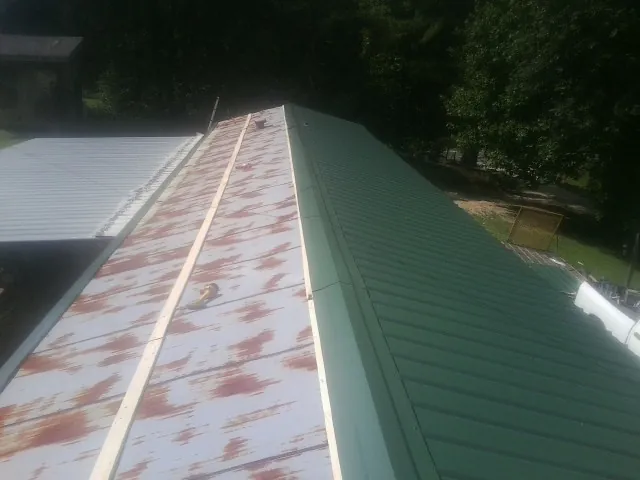 Old rusted panels beside newly installed green metal roofing — Wind Damage Roof Repair by Roofing Brothers in Grand Blanc