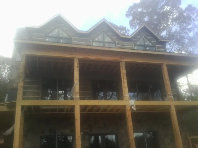 Dormers and porch framing on a large log home under construction — Roof Coating work by our crew in Grand Blanc