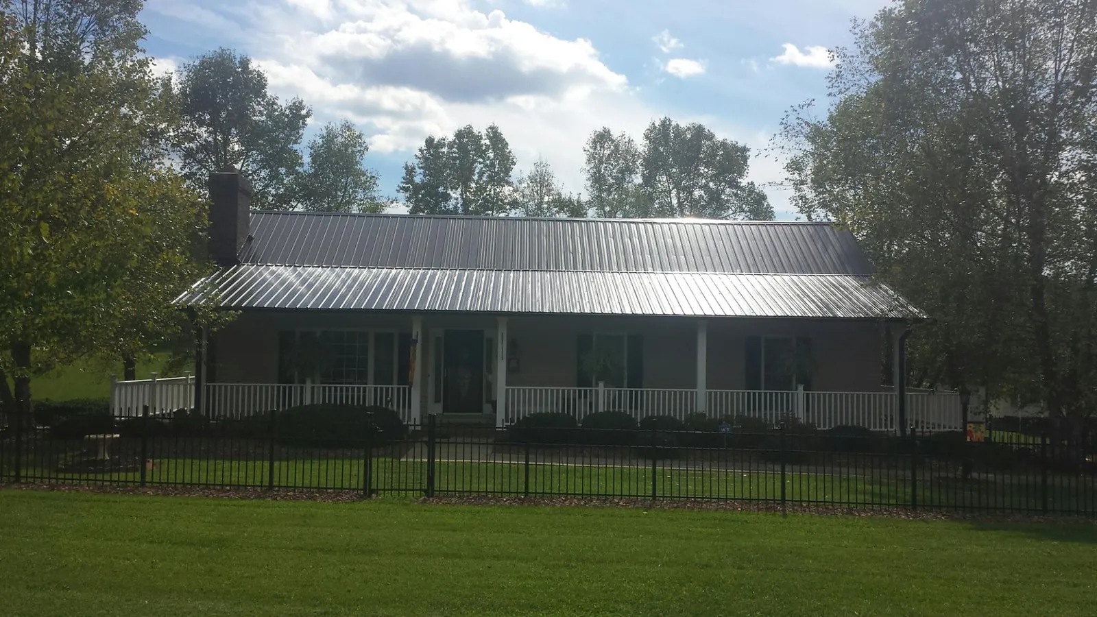 Gray metal roof on a brick ranch with a full width front porch — Gutter Guard Installation work by our crew in Grand Blanc