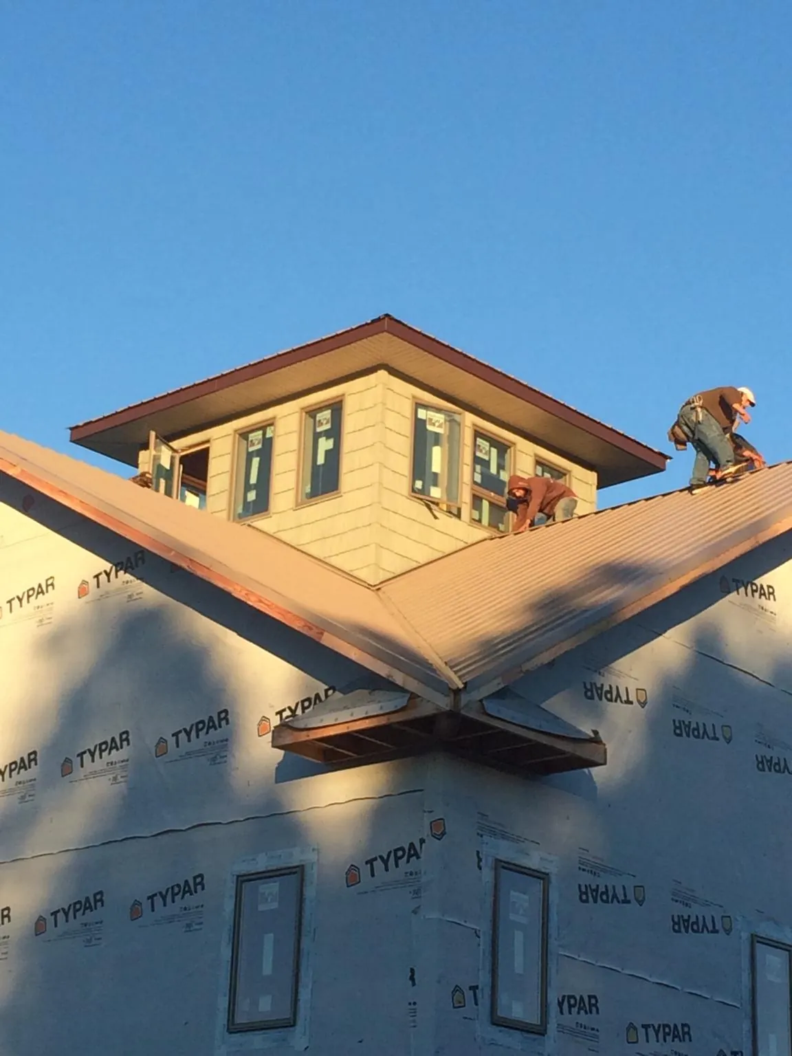 Roofers working around a rooftop cupola on a new metal roof at sunset — Roof Waterproofing in Grand Blanc by Roofing Brothers